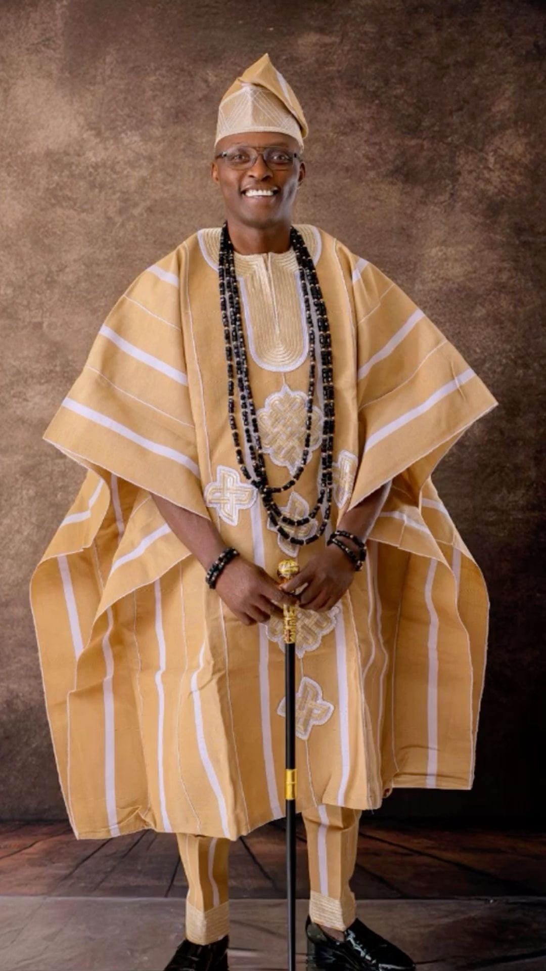 Man dressed in a golden beige agbada with a traditional cap and beads