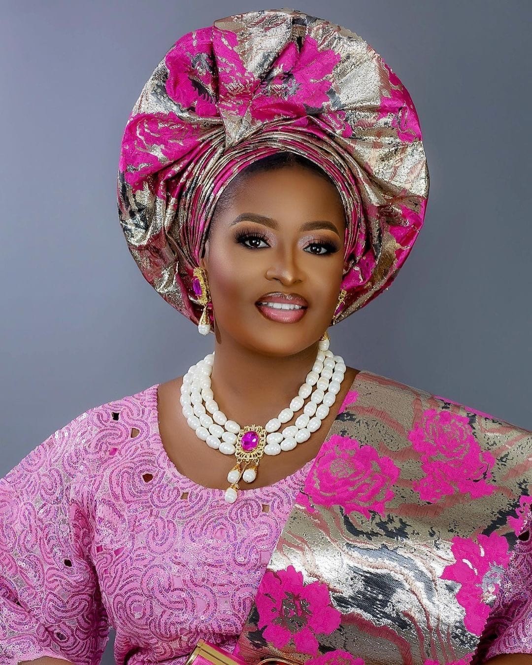 Woman in pink embroidered Nigerian occasionwear with coordinated gele and jewelry